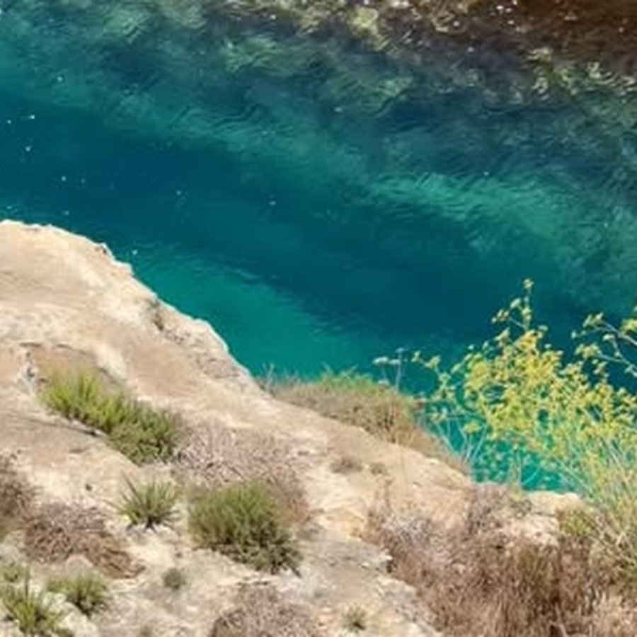 Clear turquoise water below the cliff ledge