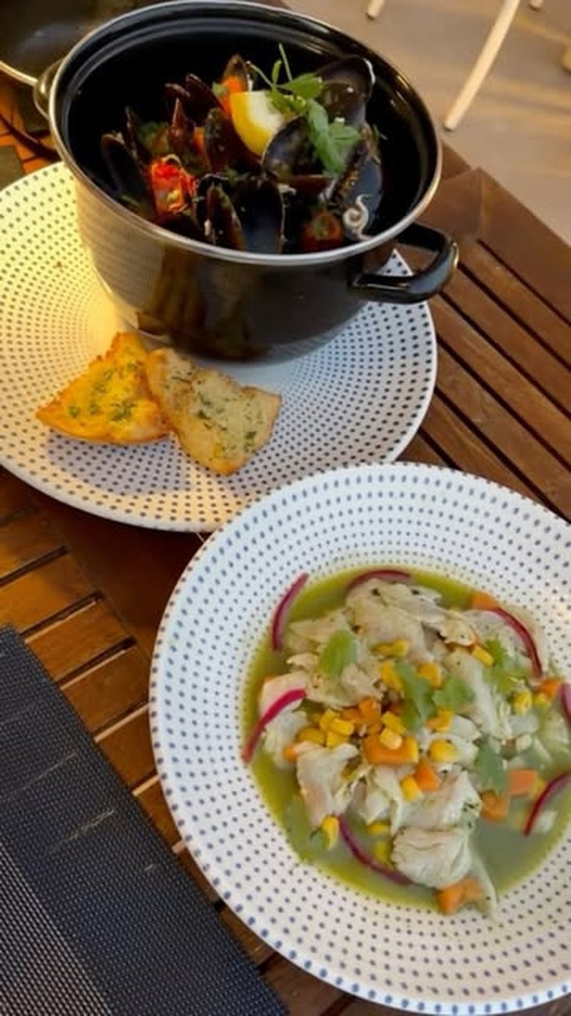 A pot of mussels with grilled bread and a plate of fish crudo